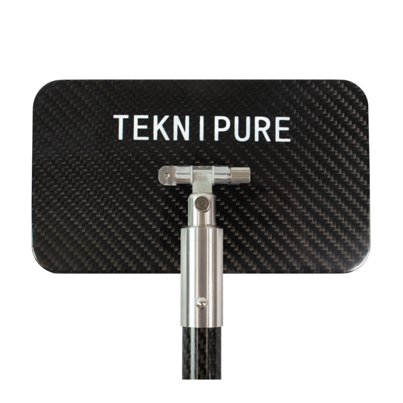 Sign reading 'TEKNI PURE' mounted on a metal joint against a carbon-fiber background.